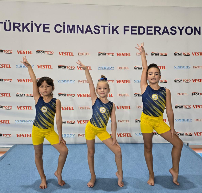 Cimnastik kıyafetiyle poz veren üç çocuk